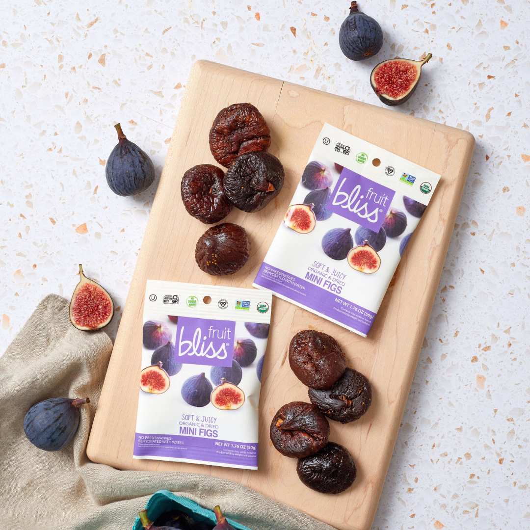 Fruit bliss mini fig packages on a wooden board with dried figs.